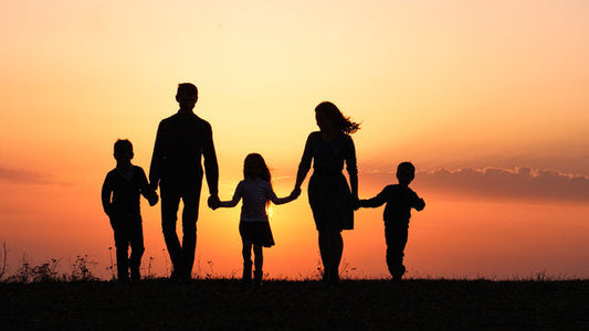 Silhouette of a family of five walking and holding hands at sunset